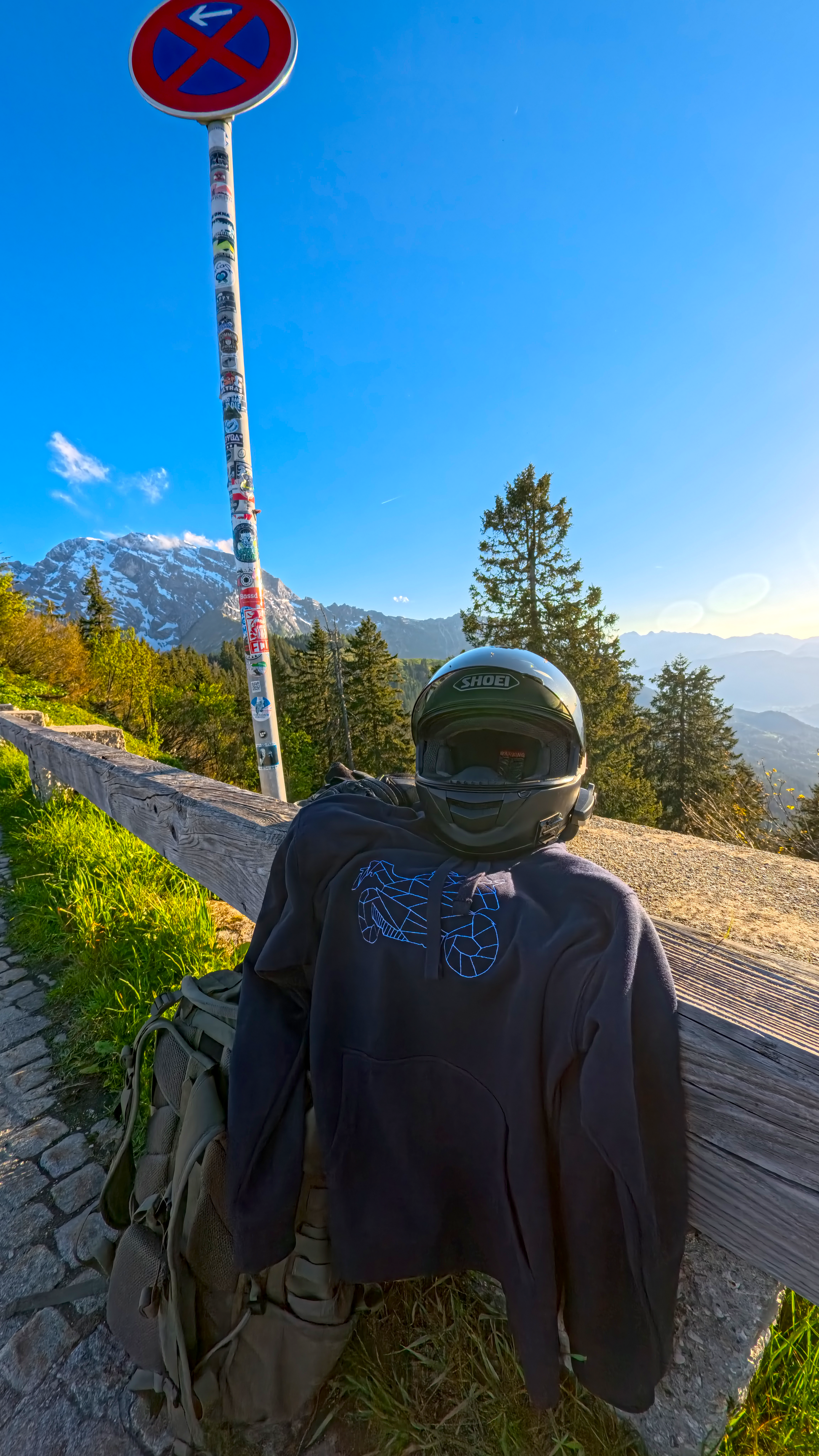Black motorcycle hoodie unisex displayed outdoors with helmet and backpack against mountain background