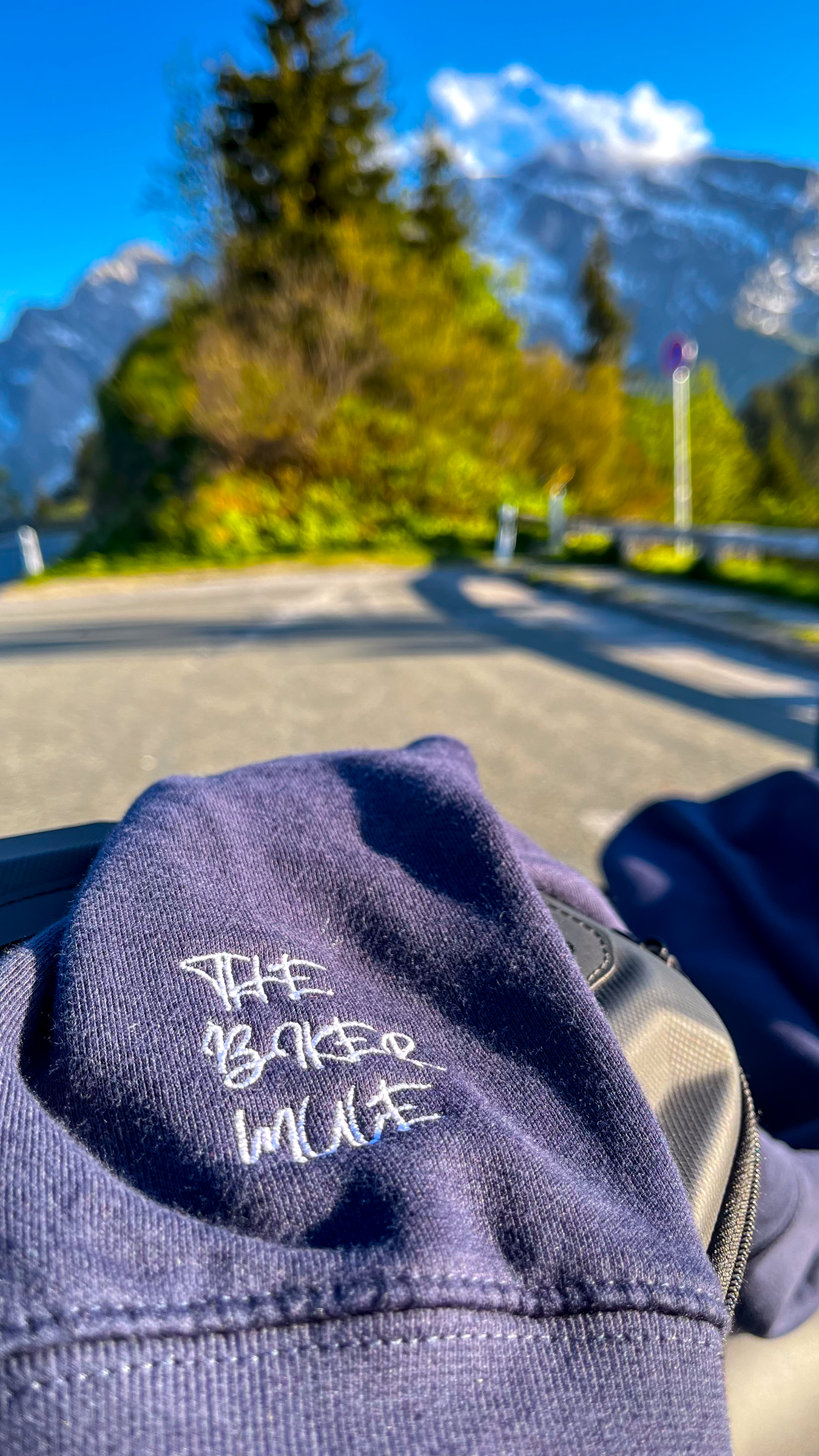Navy blue motorcycle style hoodie by The Biker Mule laid out on motorcycle seat with mountain background