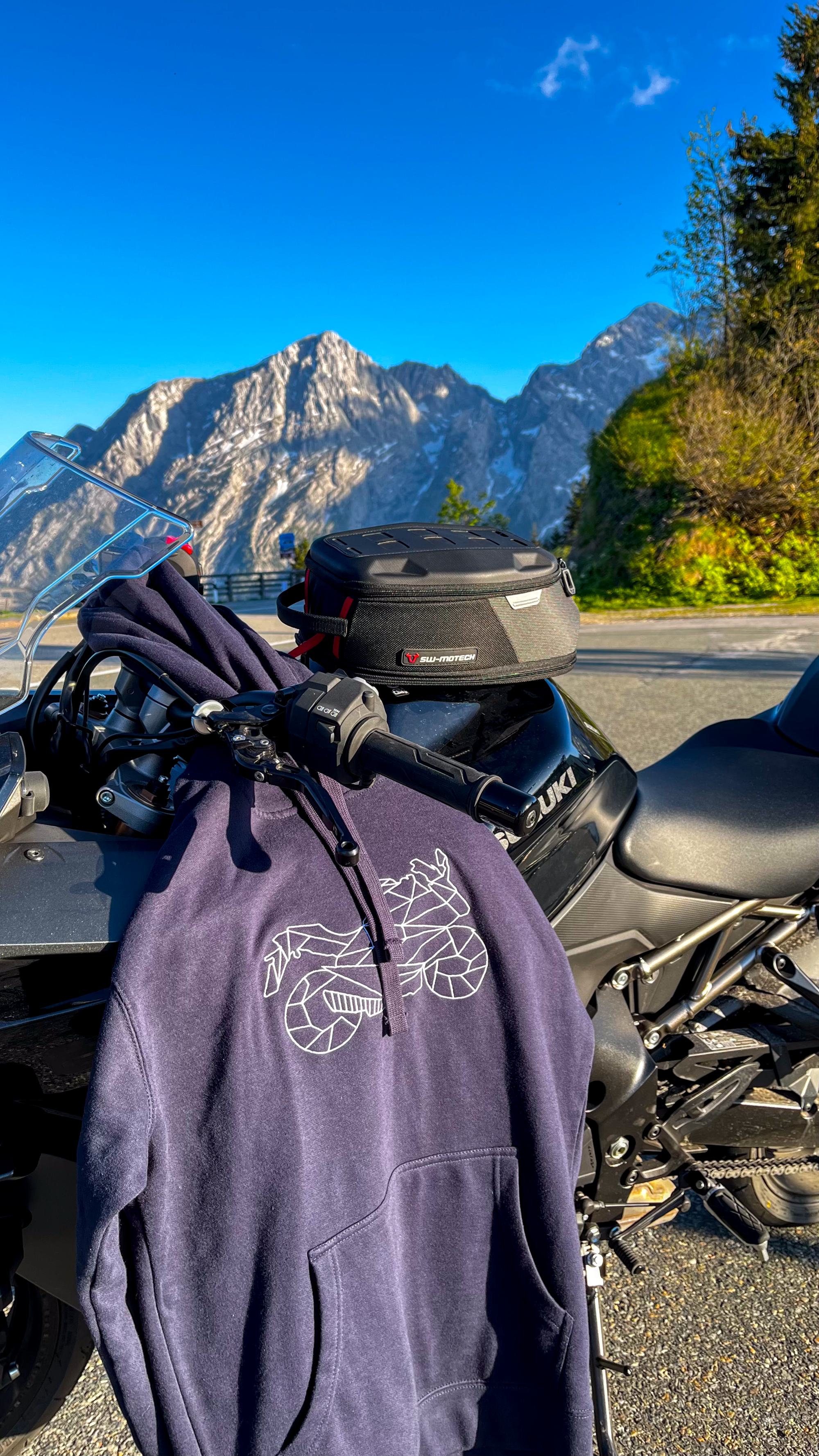 Blue motorcycle style hoodie with geometric bike design hanging on black Suzuki motorcycle outdoors