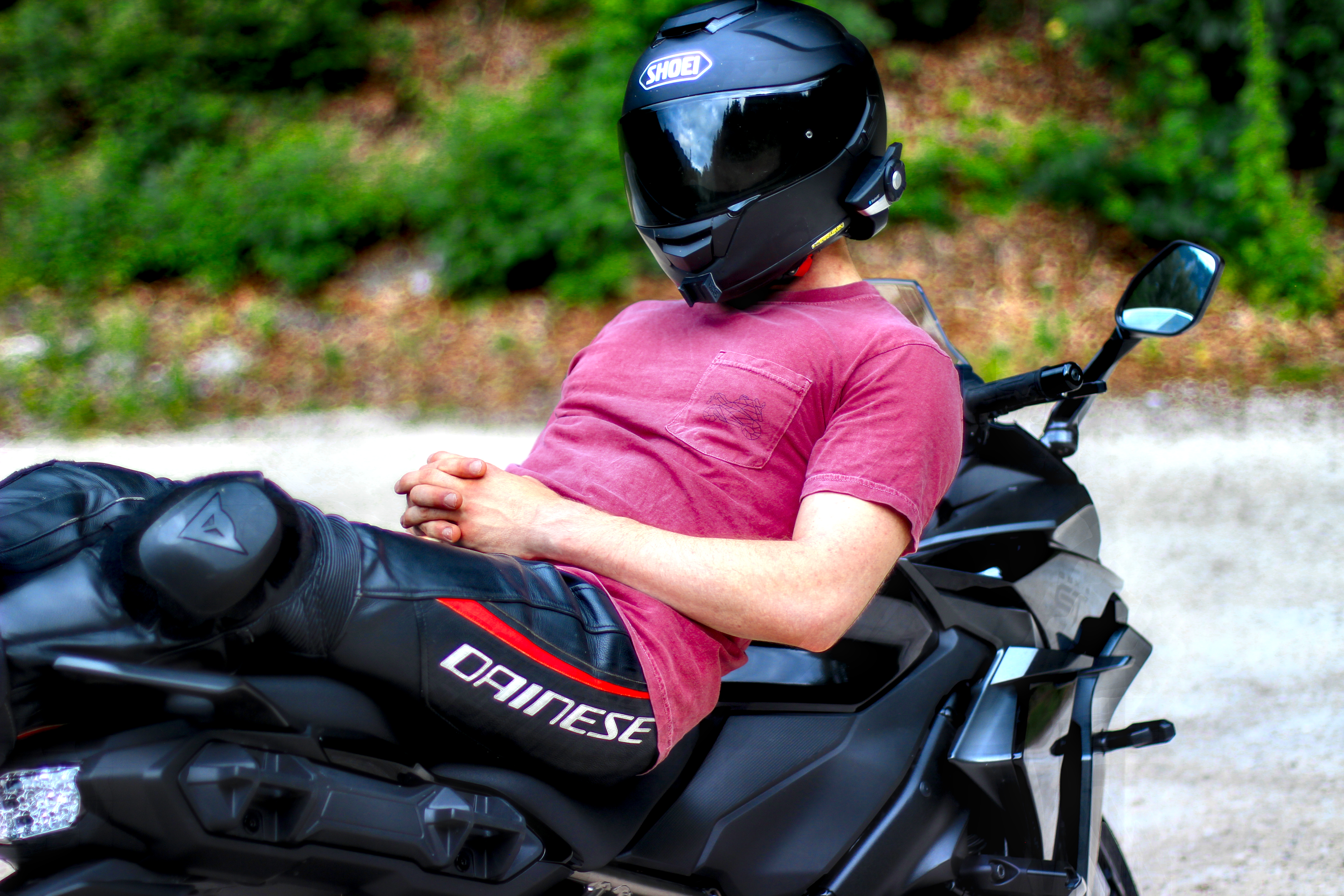 Person wearing a red motorcycle pocket shirt sitting on a black motorcycle with full gear