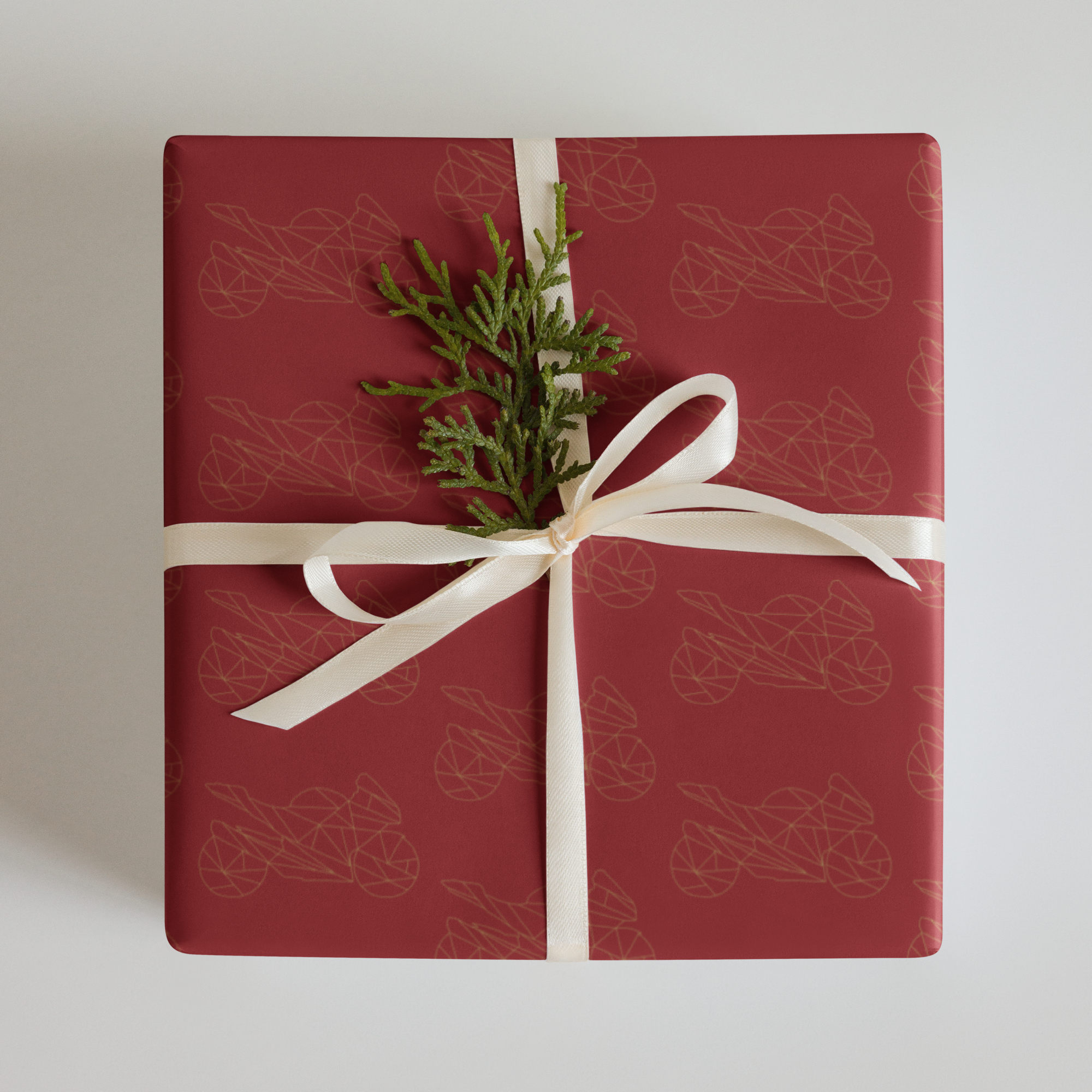 Christmas gift wrapped in red motorcycle gift wrapping paper with a ribbon and greenery accent