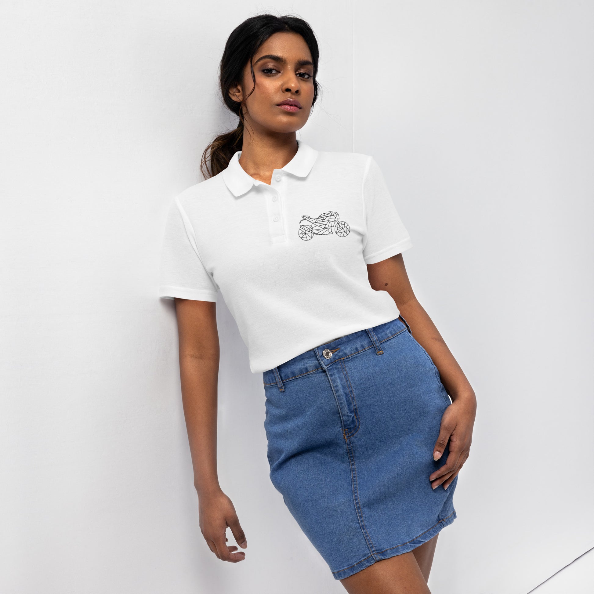 Woman wearing a white women's motorcycle polo shirt with a small motorcycle logo paired with a denim skirt